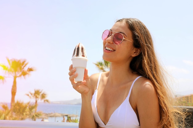 Mooie vrouw die met zonnebril roomijs eet