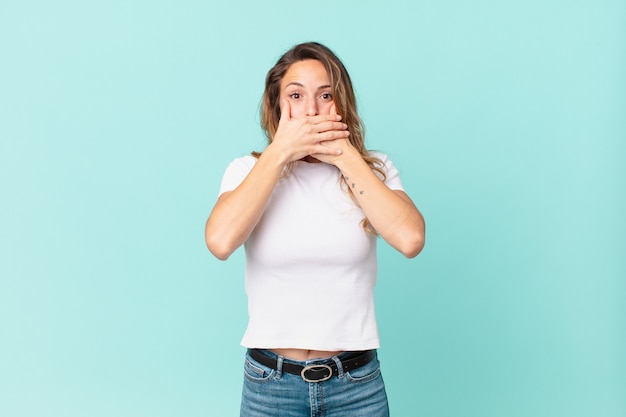 Mooie vrouw die mond bedekt met handen met een geschokte