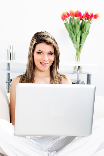 Mooie vrouw die op bank met laptop rust