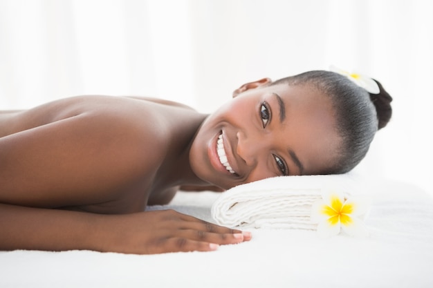 Mooie vrouw die op massagelijst ligt die bij de camera glimlacht