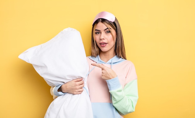 Mooie vrouw die opgewonden en verrast kijkt en naar de zijkant wijst. pyjama concept