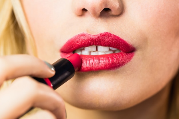 Mooie vrouw die rode lippenstift op lippen toepast