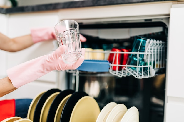 Mooie vrouw die schone gerechten uit de vaatwasser haalt.