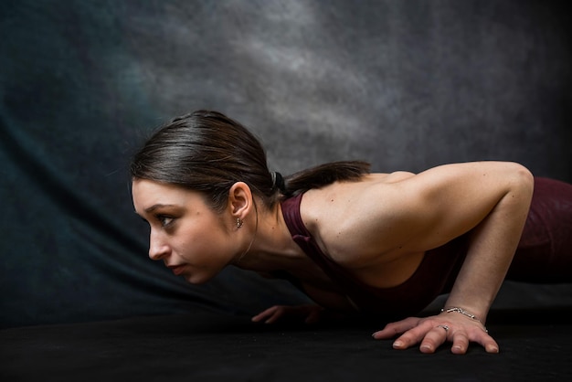 Mooie vrouw die sportkleding draagt, maakt geavanceerde yoga- of pilatesoefening geïsoleerd op zwart