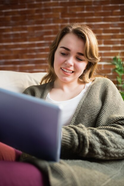 Mooie vrouw die tablet gebruiken die op de laag in de woonkamer liggen