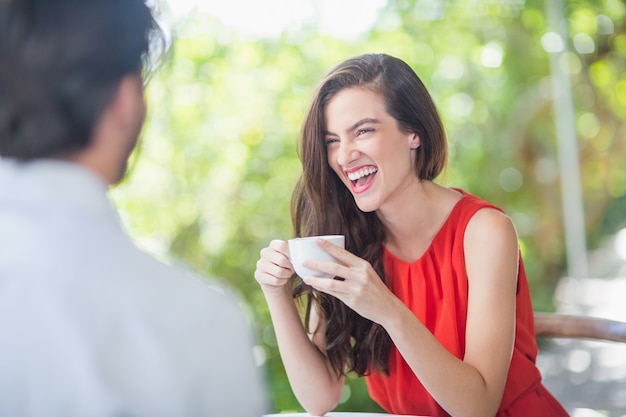 Mooie vrouw die terwijl het hebben van koffie lacht