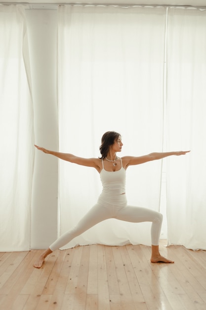 mooie vrouw die thuis yoga beoefent. vrouw in de ochtend die yoga doet in de slaapkamer.