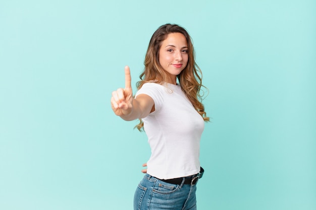 Mooie vrouw die trots en zelfverzekerd glimlacht en nummer één maakt