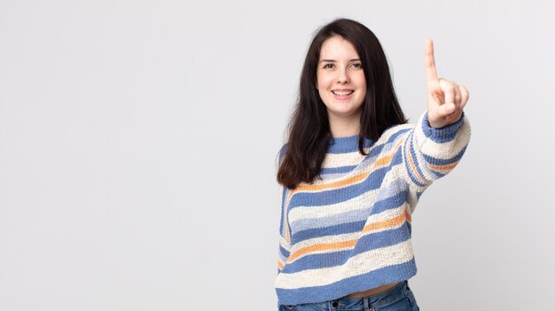 Mooie vrouw die trots en zelfverzekerd glimlacht en nummer één triomfantelijk poseert, voelt zich een leider