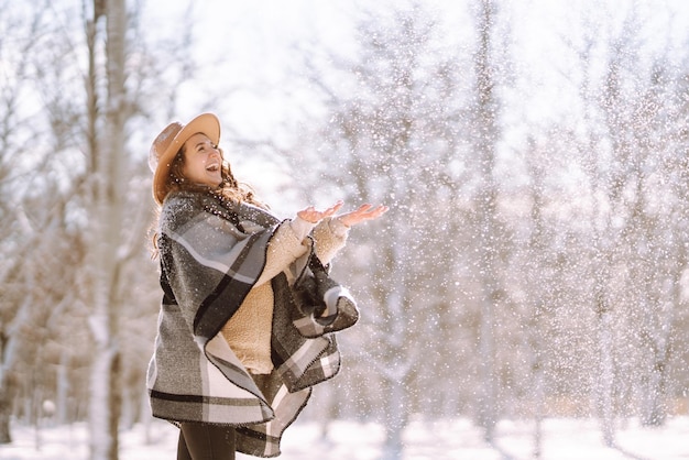 Mooie vrouw die tussen besneeuwde bomen staat en geniet van de eerste sneeuw Happy time Christmas