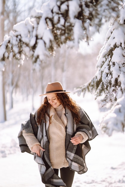 Mooie vrouw die tussen besneeuwde bomen staat en geniet van de eerste sneeuw Happy time Christmas