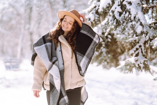 Mooie vrouw die tussen besneeuwde bomen staat en geniet van de eerste sneeuw Happy time Christmas