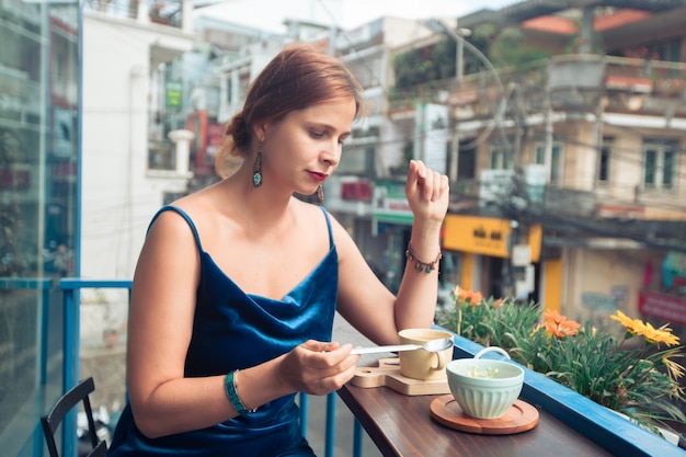 Mooie vrouw die van thee en dessert geniet op koffieterras in Dalat, Vietnam.