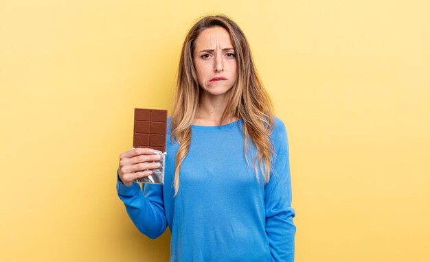 Mooie vrouw die verbaasd en verward chocoladeconcept kijkt