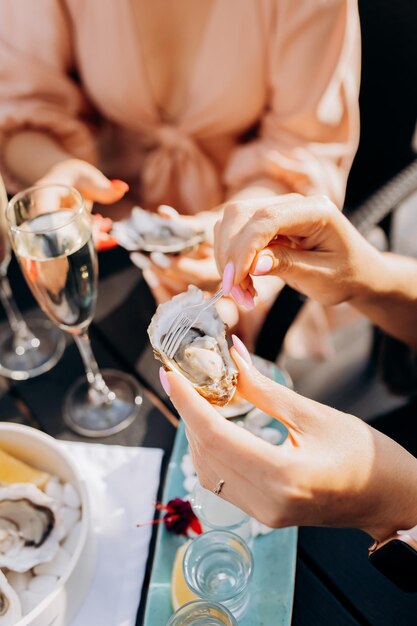 Mooie vrouw die verse oesters eet en gekoelde prosecco-wijn drinkt op de zomerzonsondergang in restaurant zeevruchten delicatessen