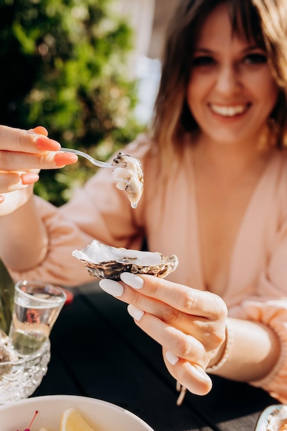 Mooie vrouw die verse oesters eet en gekoelde prosecco-wijn drinkt op de zomerzonsondergang in restaurant zeevruchten delicatessen