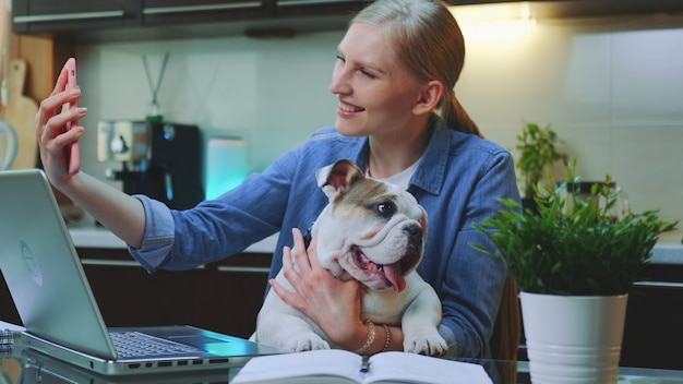 Mooie vrouw die video op smartphone met een kleine hond op haar handen telefoneert