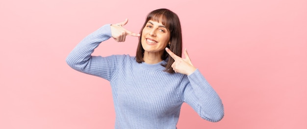 mooie vrouw die vol vertrouwen glimlacht en wijst naar een brede glimlach, een positieve, ontspannen, tevreden houding