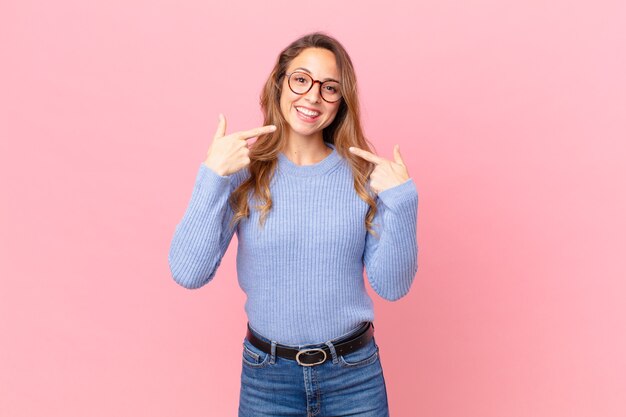 Mooie vrouw die vol vertrouwen glimlacht en wijst naar haar eigen brede glimlach