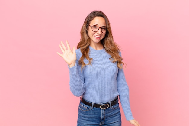 Mooie vrouw die vrolijk lacht, met de hand zwaait, je verwelkomt en begroet