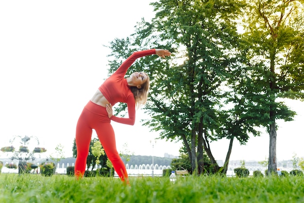 Mooie vrouw die yoga-oefeningen in het park doet