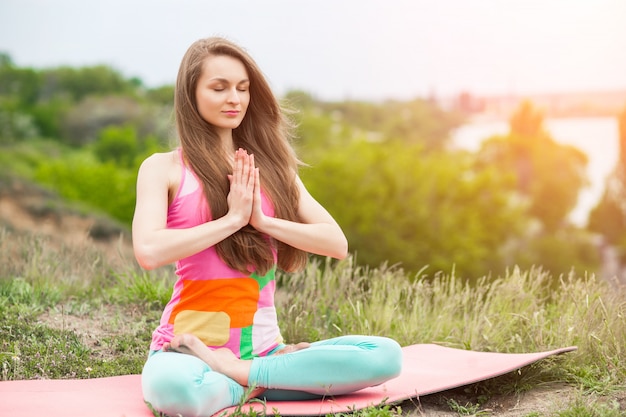 Mooie vrouw die yogaoefeningen op aardlandschap doet