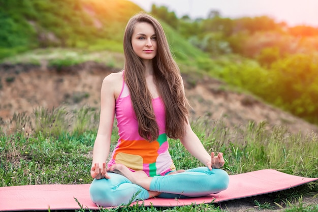 Foto mooie vrouw die yogaoefeningen op aardlandschap doet