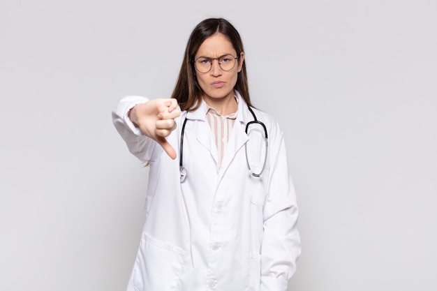 Mooie vrouw die zich boos, boos, geïrriteerd, teleurgesteld of ontevreden voelt, duimen naar beneden laat zien met een serieuze blik