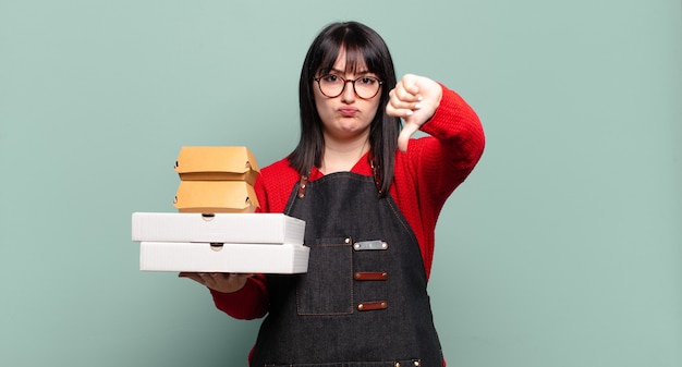 Mooie vrouw die zich boos, boos, geïrriteerd, teleurgesteld of ontevreden voelt, duimen naar beneden laat zien met een serieuze blik