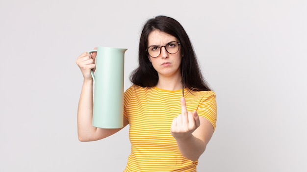 Foto mooie vrouw die zich boos, geïrriteerd, opstandig en agressief voelt en een thermoskan koffie vasthoudt