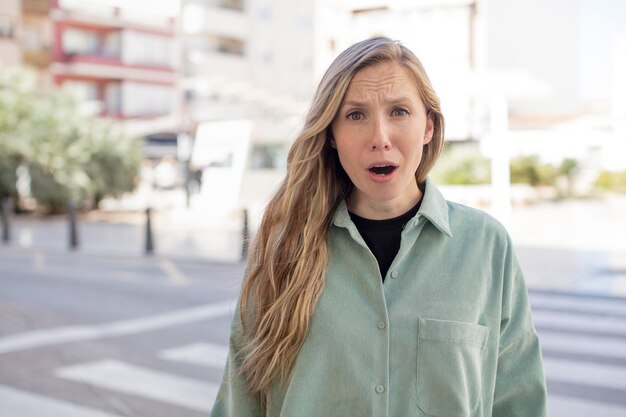 Foto mooie vrouw die zich doodsbang en geschokt voelt met de mond wijd open van verbazing