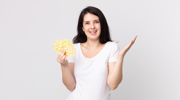 Mooie vrouw die zich gelukkig en verbaasd voelt over iets ongelooflijks en een dieetrijstwafels vasthoudt