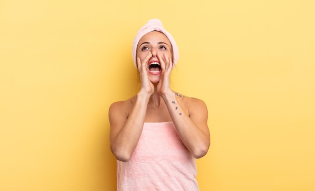 Mooie vrouw die zich gelukkig voelt, een grote schreeuw geeft met de handen naast de mond. douche en beauty concept