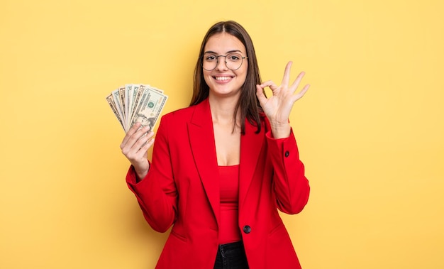 mooie vrouw die zich gelukkig voelt, goedkeuring toont met een goed gebaar. dollar biljetten concept