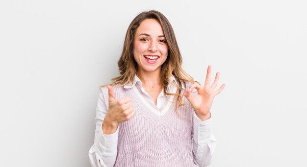 Mooie vrouw die zich gelukkig voelt, verbaasd, tevreden en verrast, oke tonen en duimen omhoog gebaren glimlachen