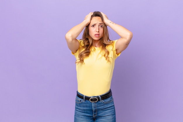 Mooie vrouw die zich gestrest, angstig of bang voelt, met de handen op het hoofd