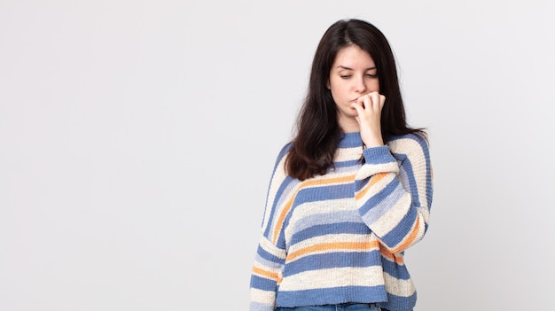 mooie vrouw die zich serieus, bedachtzaam en bezorgd voelt, zijwaarts starend met de hand tegen de kin gedrukt