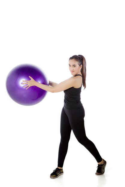 Mooie vrouw die zich uitstrekt met fitness bal op studio