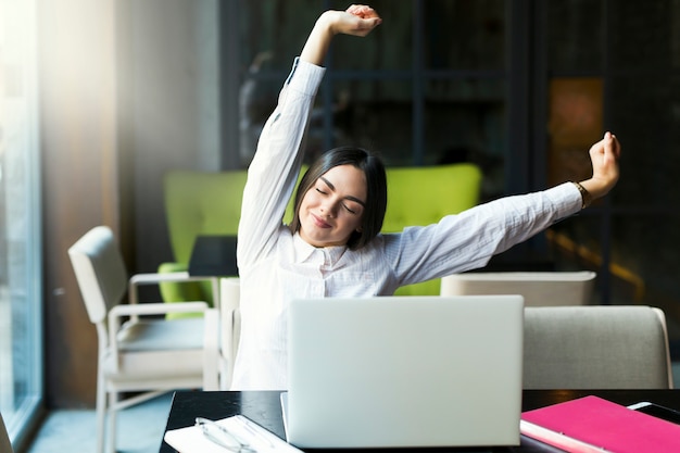 Mooie vrouw die zich uitstrekt op laptop