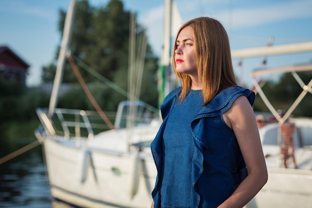 Mooie vrouw die zich voordeed op de jachthaven op een zonnige zomerdag aan de rivier