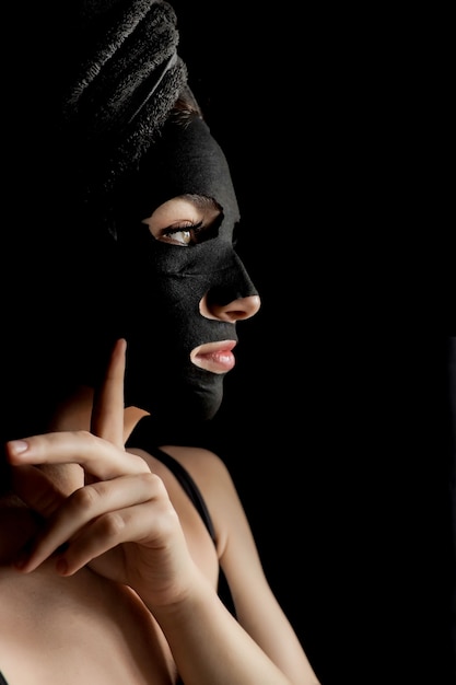 Mooie Vrouw die Zwart Gezichtsmasker toepast. Schoonheidsbehandelingen. Het close-upportret van Kuuroordmeisje past Clay Facial-masker toe