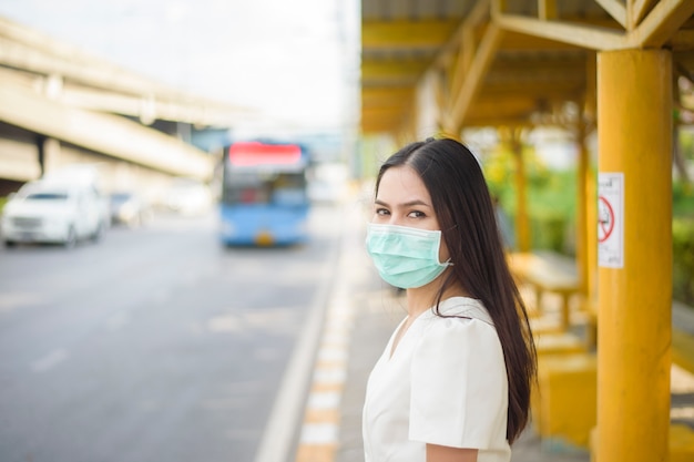 Mooie vrouw draagt gezichtsmasker in bushalte