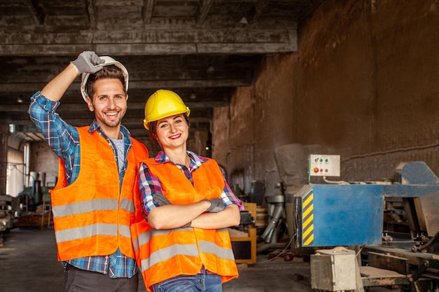 Mooie vrouw en aantrekkelijke man fabrieksarbeiders poseren samen glimlachend binnenshuis een oude fabriekswinkel Teamwork concept