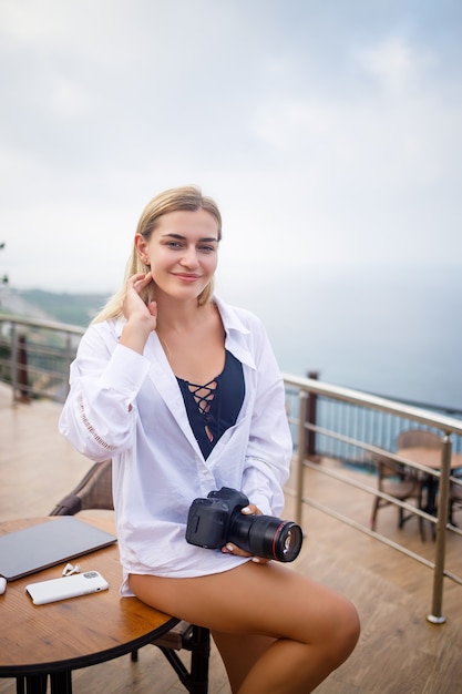 Mooie vrouw fotograaf blogger op vakantie, werken met laptop bij het zwembad. Freelance werken op afstand