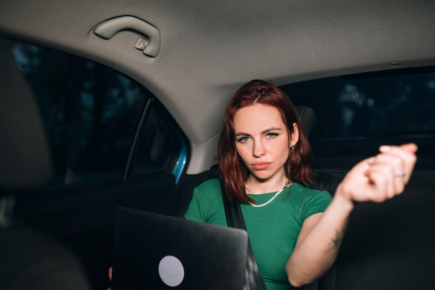 Mooie vrouw gebruikt laptop terwijl ze op de achterbank zit