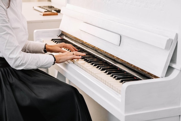 Mooie vrouw gekleed in witte jurk spelen op witte piano