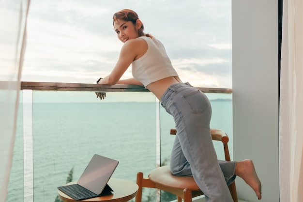 Mooie vrouw geniet van het uitzicht op zee vanaf het balkon van het hotel