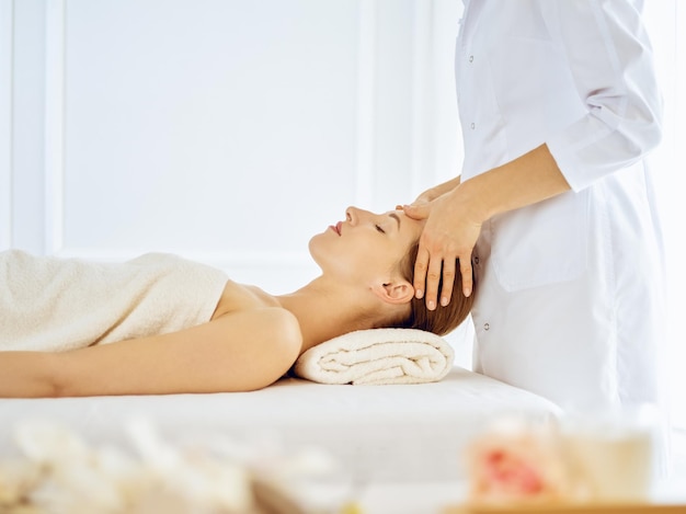 Mooie vrouw genieten van gezichtsmassage met gesloten ogen. Spa-behandelingsconcept in de geneeskunde.