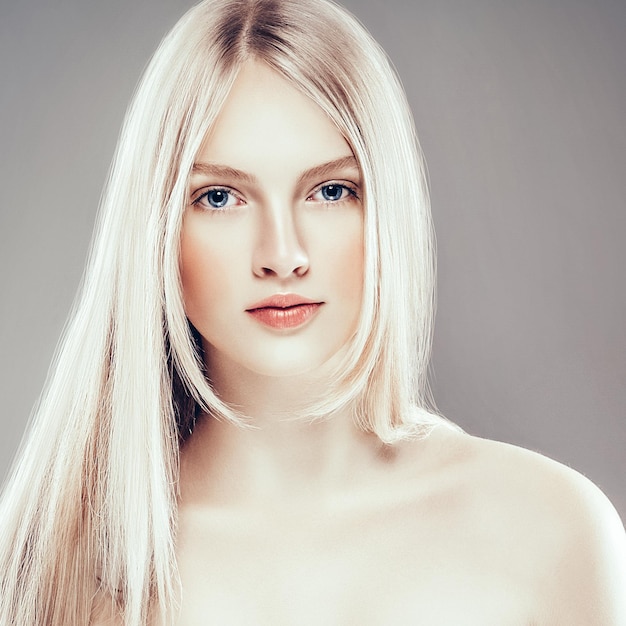 Mooie vrouw gezicht portret schoonheid huidverzorging concept met lang blond haar. Fashion Beauty Model met mooi kapsel over grijze achtergrond