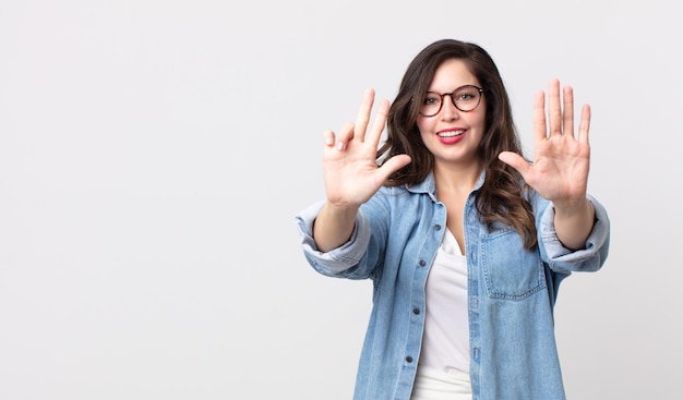 Mooie vrouw glimlachend en vriendelijk kijkend, nummer acht of achtste tonend met hand naar voren, aftellend